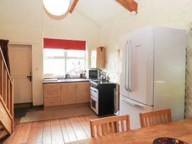 A kitchen with wooden cabinets a white refrigerator a black oven and a wooden dining table at Dovetail Cottage in Llangollen