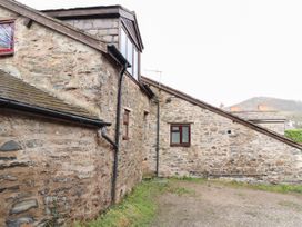 An exterior view of a stone building with multiple small windows and a sloping roof at Dovetail Cottage in Llangollen