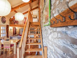 A living room with stairs and dining area at Dovetail Cottage in Llangollen