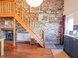 A living room with a staircase and wooden table at Dovetail Cottage in Llangollen