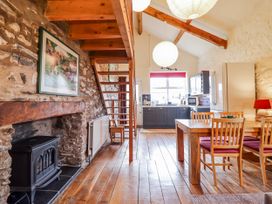A dining room with a staircase and kitchen at Dovetail Cottage in Llangollen
