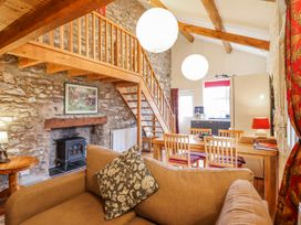 A living room with a staircase and table at Dovetail Cottage in Llangollen