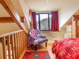 A bedroom with a bed and armchair at Dovetail Cottage Llangollen