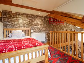 A bedroom with a bed and stone walls at Dovetail Cottage in Llangollen
