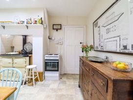 A kitchen with a stove, cabinet, and flowers at Murmur Y Don in Harlech