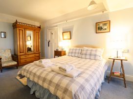 A bedroom with a bed, wardrobe, and armchair at Murmur Y Don in Harlech