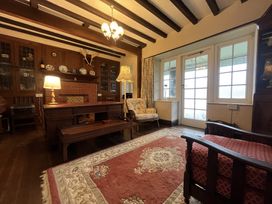 A living room with wooden furniture and a rug at Murmur Y Don in Harlech