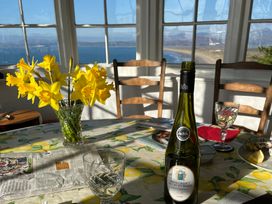 A dining room with flowers and wine on the table at Murmur Y Don in Harlech