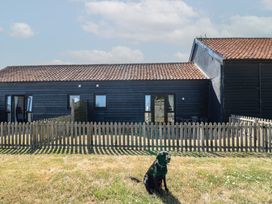 A house with a dog in front and a fence at Tawny Owl Barn Shipdham near Dereham