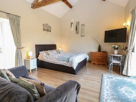 A bedroom with a bed, sofa, and television at Tawny Owl Barn in Shipdham near Dereham