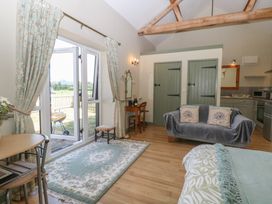 A living room with a sofa and kitchenette at Tawny Owl Barn in Shipdham near Dereham