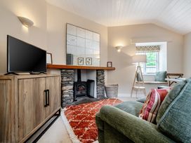 A living room with a television and stone fireplace at Can Brow at the Graythwaite Estate near Hawkshead