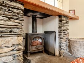 A living room with a wood stove and stone surround at Can Brow at the Graythwaite Estate near Hawkshead