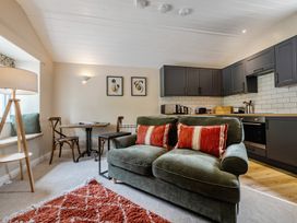 A living room with a sofa and kitchen in Can Brow at the Graythwaite Estate near Hawkshead