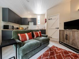 A living room with a sofa and kitchen cabinets at Can Brow at the Graythwaite Estate near Hawkshead