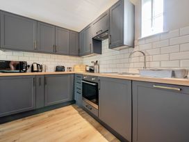 A kitchen with cabinets, microwave, kettle, and sink at Can Brow at the Graythwaite Estate near Hawkshead