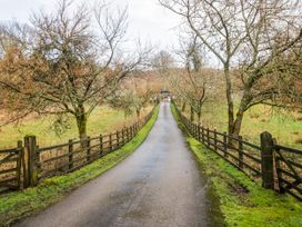 A driveway lined with trees and fence leading to a house at Jubilee in Graythwaite near Hawkshead