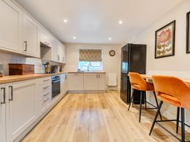 A kitchen with cabinets, a sink, and bar stools at Jubilee at the Graythwaite Estate Graythwaite near Hawkshead
