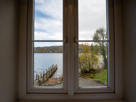 A view of a lake and dock through a window at Hammerhole in Graythwaite near Hawkshead