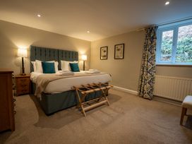 A bedroom with a bed, bedside tables, and window at Hammerhole in Graythwaite near Hawkshead