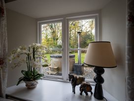 A window with an orchid plant and lamp overlooking a hot tub at Hammerhole near Graythwaite