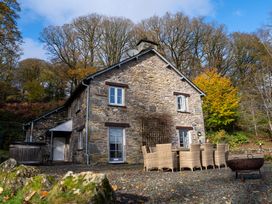 An outdoor view of a stone house with a dining table and chairs at Hammerhole in Graythwaite near Hawkshead
