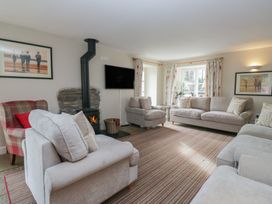 A living room with sofas, an armchair, and a fireplace at Hammerhole in Graythwaite near Hawkshead
