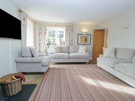 A living room with a sofa, armchair, and television at Hammerhole in Graythwaite near Hawkshead