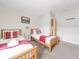 A bedroom with two beds and a bedside table at Hammerhole at the Graythwaite Estate near Hawkshead
