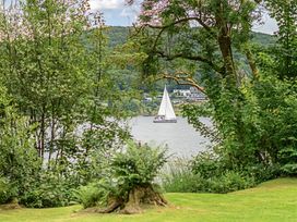 A sailboat on the water surrounded by trees at Hammerhole at the Graythwaite Estate Graythwaite Estate near Hawkshead