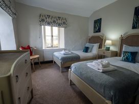 A bedroom with two beds and a dressing table at Hullet Hall in Graythwaite near Hawkshead