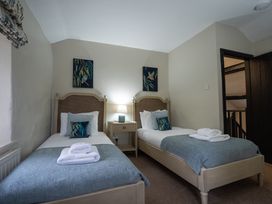 A bedroom with two beds and a bedside table at Hullet Hall in Graythwaite near Hawkshead