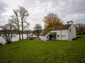 A house next to a lake with grass and trees at Hullet Hall in Graythwaite near Hawkshead