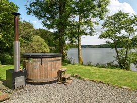 A hot tub with a wooden structure beside a lake at Hullet Hall at the Graythwaite Estate near Hawkshead