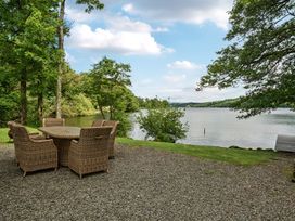 An outdoor seating area with a table and chairs near a lake at Hullet Hall at the Graythwaite Estate near Hawkshead