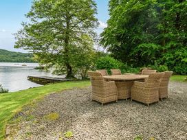 A dining table and chairs by the water at Hullet Hall at the Graythwaite Estate near Hawkshead