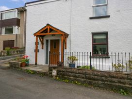 The entrance of a white building with a wooden door and a small porch with pots of flowers outside at Fox Barn in Staveley
