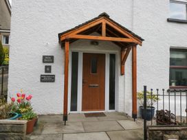 Entrance with wooden door and wooden porch surrounded by flower pots at Fox Barn in Staveley