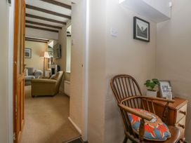 A hallway with a wooden chair and side table next to a living room with armchairs and a standing lamp at Fox Barn in Staveley