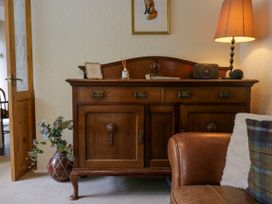 A wooden sideboard with a lamp plant and speaker next to a leather chair at Fox Barn in Staveley