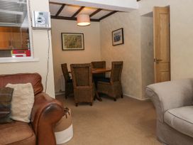 A living room with a brown leather sofa and a dining area with wicker chairs at Fox Barn in Staveley