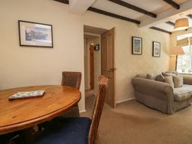A living area with a wooden round table and woven chairs next to a beige sofa with cushions at Fox Barn in Staveley