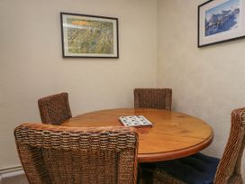 A dining area with a round wooden table and four wicker chairs with cushions at Fox Barn in Staveley