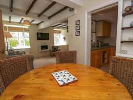 A dining area with wooden table and wicker chairs facing a living room with sofas and a wall mounted tv at Fox Barn in Staveley