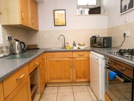 A kitchen with wooden cabinets a sink microwave dishwasher oven and kettle at Fox Barn in Staveley