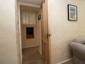 A hallway with a wooden door partially open a blackboard on the far wall and a couch arm with a framed picture hanging above at Fox Barn in Staveley