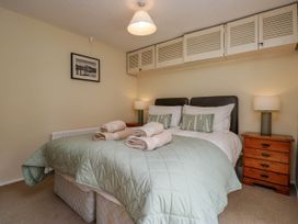A bedroom with a double bed nightstands with lamps and built in cupboards above the bed at Fox Barn in Staveley