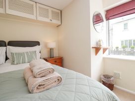 A bedroom with a bed with folded towels on it a bedside table with a lamp a window with a shelf and an alarm clock a round mirror and a wastebasket at Fox Barn in Staveley