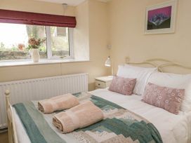 A bedroom with a bed with folded towels on a patterned blanket and a window with flowers in a vase at Fox Barn in Staveley