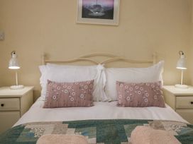 A bed with white pillows and flower patterned cushions between two bedside tables with lamps at Fox Barn in Staveley